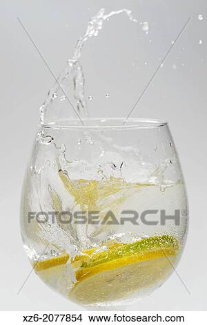 Picture - Citrus fruits, lemon and lime slices splashing in a glass on white background.. Fotosearch