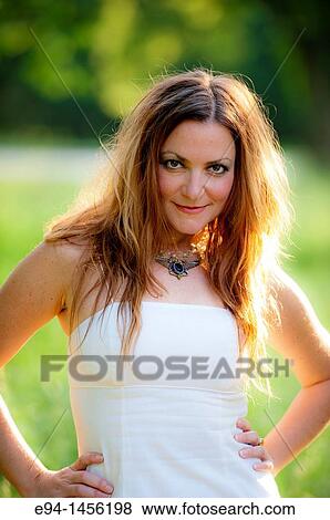 Stock Photo - Close portrait of a 36 year old brunette woman in a white summer dress looking at the camera. Fotosearch