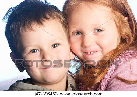 Stock Image - Close up headshot of 4 year old girl and 3 year old boy, smiling into camera. Fotosearch