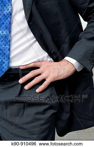 Stock Photograph - Close-up image of a caucasian man's hand at his hips in the center of the image with the man wearing business suit, white shirt and blue tie, Hong Kong, East Asia. Fotosearch