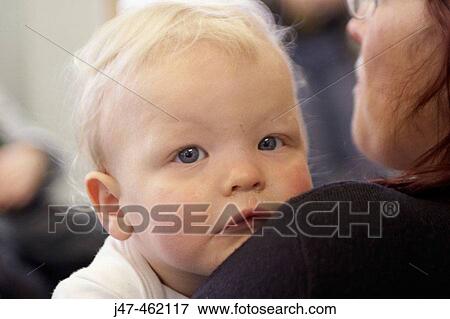 Close up of 18 month old baby boy looking seriously into camera over his mothers shoulder View Large Photo Image Stock Photo - Close up of 18 month old baby boy looking seriously into camera over his mothers shoulder. Fotosearch