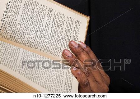 Stock Photography - Close-up of a black woman's hand holding a book. Fotosearch