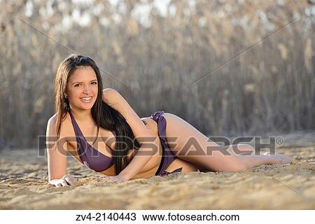 Close-up of a good looking young woman wearing a bikini and lying in the sand of a llittle beach on a sunny day in early spring. View Large Photo Image Stock Image - Close-up of a good looking young woman wearing a bikini and lying in the sand of a llittle beach on a sunny day in early spring.. Fotosearch