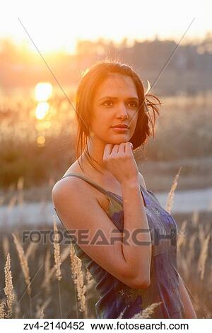 Close-up of a good looking young woman in the grass at sunset in early spring. View Large Photo Image Stock Image - Close-up of a good looking young woman in the grass at sunset in early spring.. Fotosearch