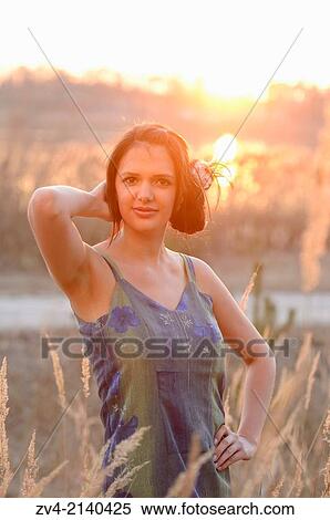 Close-up of a good looking young woman in the grass at sunset in early spring. View Large Photo Image Stock Photography - Close-up of a good looking young woman in the grass at sunset in early spring.. Fotosearch