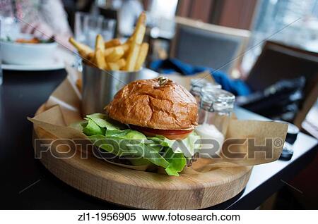 Stock Photography - Close up of a Hamburger on wood plate shallow depth of field.. Fotosearch