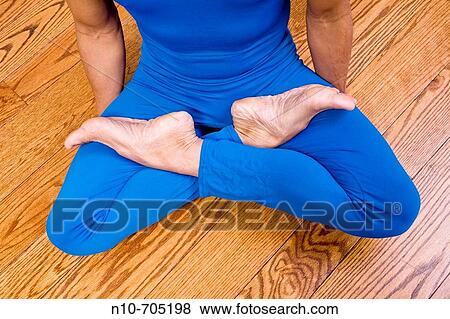 Stock Photo - Close-up of a man sitting cross-legged on a hardwood floor. Fotosearch