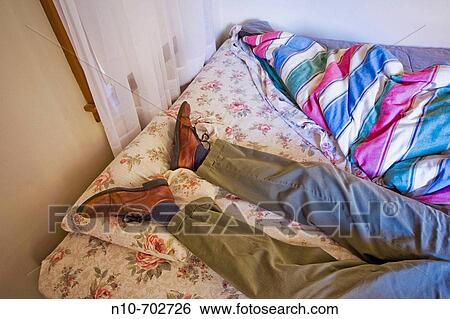 Close-up of a man's feet and legs resting on the pillow of an unmade bed. View Large Photo Image Stock Photograph - Close-up of a man's feet and legs resting on the pillow of an unmade bed.. Fotosearch