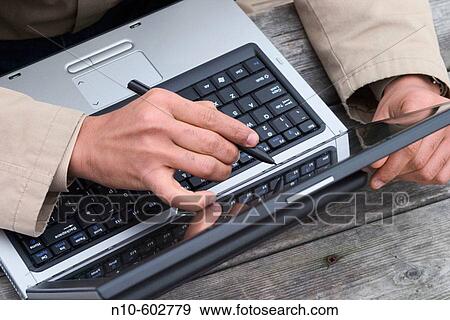Stock Photo - Close-up of a man's hand using a pen device on the screen of his laptop computer.. Fotosearch