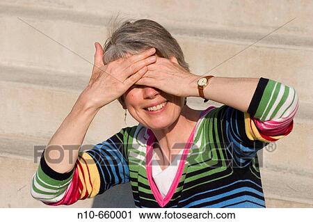 Close-up of a middle-aged woman covering her eyes with her hands. View Large Photo Image Stock Image - Close-up of a middle-aged woman covering her eyes with her hands.. Fotosearch