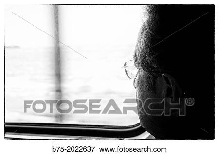 Stock Photo - Close-up of a person's face looking through the window of a train. Fotosearch