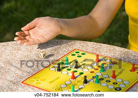 Picture - Close up of a player's hand tossing a dice at a board game. Fotosearch