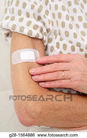 Close up of a Senior woman looking at a dressing on her arm View Large Photo Image Stock Photograph - Close up of a Senior woman looking at a dressing on her arm. Fotosearch