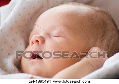 Picture - Close-up of a sleeping newborn bundled in a blanket. Fotosearch