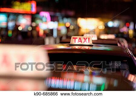 Stock Photograph - Close up of a taxi sign on the roof of taxis, standing in a row in the amusement center of Wanchai, Hong Kong Island, Hong Kong, China, East Asia. Fotosearch