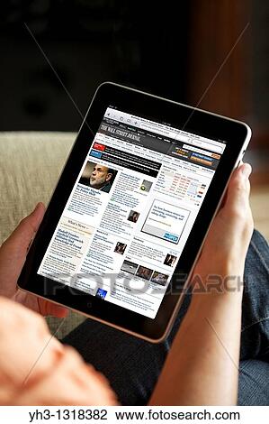 Stock Image - Close up of a woman reading Wall Street Journal online news from an iPad. Fotosearch