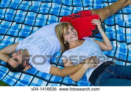 Close up of a young couple lying on a blanket in the garden, smiling, Germany, Europe View Large Photo Image Stock Photography - Close up of a young couple lying on a blanket in the garden, smiling, Germany, Europe. Fotosearch