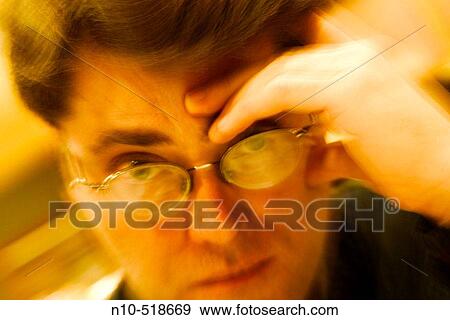 Close-up of a young man, wearing glasses, with his hand resting on his head View Large Photo Image Stock Photo - Close-up of a young man, wearing glasses, with his hand resting on his head. Fotosearch