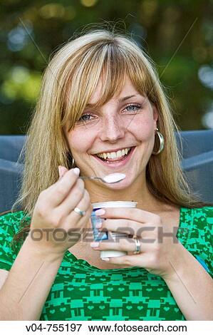 Close up of a young woman eating yoghurt, smiling View Large Photo Image Stock Photo - Close up of a young woman eating yoghurt, smiling. Fotosearch