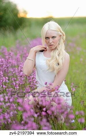 Close-up of a young woman in a flower field at sunset. View Large Photo Image Picture - Close-up of a young woman in a flower field at sunset.. Fotosearch