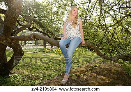Close-up of a young woman on a tree in spring. View Large Photo Image Picture - Close-up of a young woman on a tree in spring.. Fotosearch