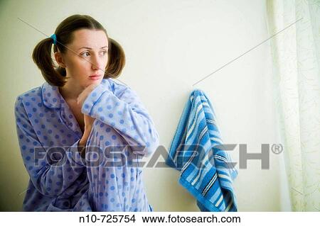 Close-up of a young woman sitting next to a towel in her bathroom View Large Photo Image Picture - Close-up of a young woman sitting next to a towel in her bathroom. Fotosearch