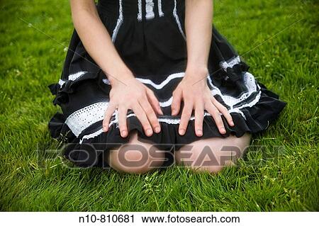 Close-up of a young woman sitting on the grass at a park View Large Photo Image Stock Image - Close-up of a young woman sitting on the grass at a park. Fotosearch