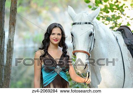 Close-up of a young woman standing beside a white Bavarian Warmblood horse. View Large Photo Image Picture - Close-up of a young woman standing beside a white Bavarian Warmblood horse.. Fotosearch