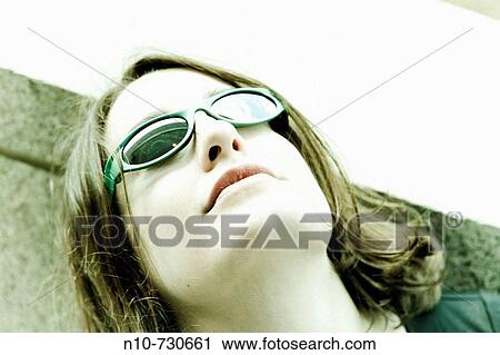Stock Image - Close-up of a young woman wearing sunglasses.. Fotosearch