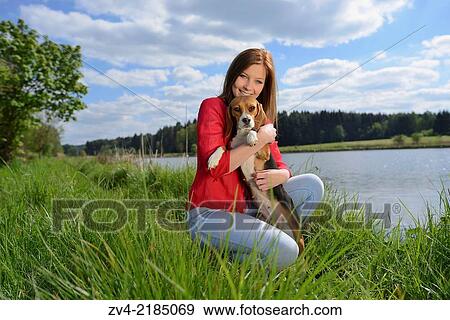 Stock Photo - Close-up of a young woman with her Beagle dog in spring.. Fotosearch