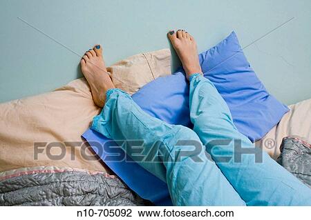 Close-up of a young woman's legs and bare feet as she lies on her bed View Large Photo Image Stock Image - Close-up of a young woman's legs and bare feet as she lies on her bed. Fotosearch