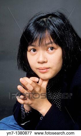 Stock Photo - close up of asian girl with hands clasped and looking hopefully to our right. Fotosearch