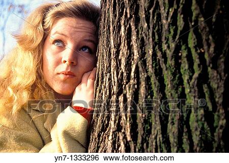 close up of blond girl leaning against tree and looking into the distance View Large Photo Image Stock Photograph - close up of blond girl leaning against tree and looking into the distance. Fotosearch