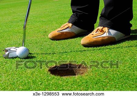 Stock Image - Close-up of Golfer Putting into Hole. Fotosearch