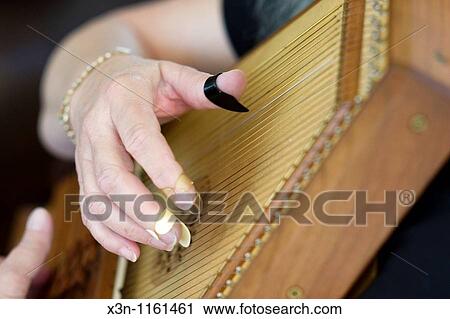 Stock Image - Close up of hand playing autoharp. Fotosearch
