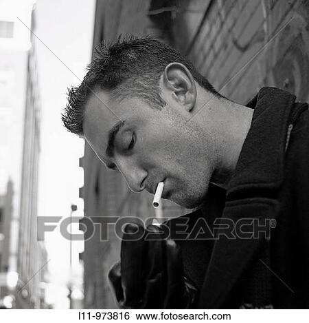 Close-up of man in alley, lighting a cigarette View Large Photo Image Stock Photograph - Close-up of man in alley, lighting a cigarette. Fotosearch