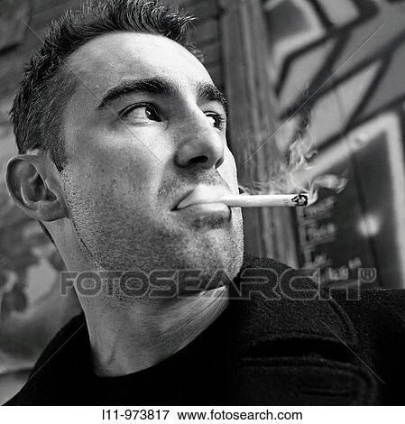Stock Photo - Close-up of man in alley, smoking a cigarette. Fotosearch