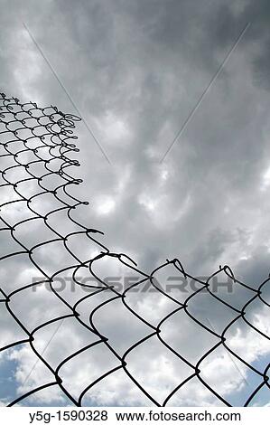 close up of metal wire fence barrier and dark cloudy moody sky View Large Photo Image Stock Photo - close up of metal wire fence barrier and dark cloudy moody sky. Fotosearch