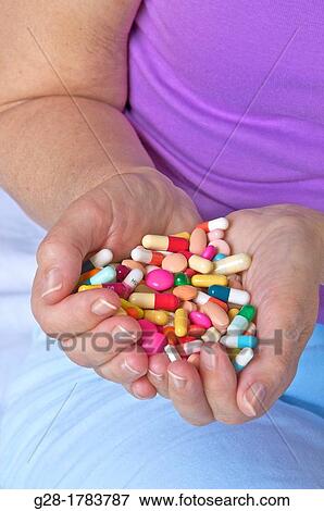 Close up of Senior womann holding a handful of colored pills and capsules in her hands, sitting on her bed in her bedroom View Large Photo Image Stock Photo - Close up of Senior womann holding a handful of colored pills and capsules in her hands, sitting on her bed in her bedroom. Fotosearch