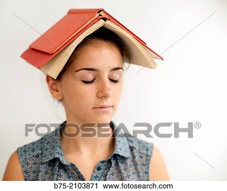 Stock Image - Close-up of teenager girl with peaceful expression and two books on the head.. Fotosearch