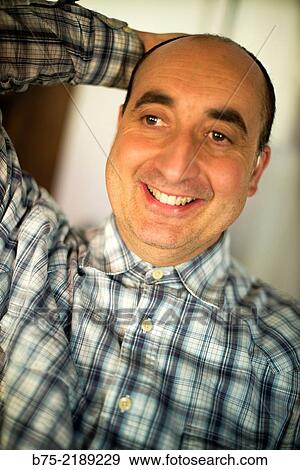 Close-up of the face of a 40-year-old Caucasian man, smiling and positive attitude, with one hand on his head and wearing plaid shirt. View Large Photo Image Stock Photo - Close-up of the face of a 40-year-old Caucasian man, smiling and positive attitude, with one hand on his head and wearing plaid shirt.. Fotosearch