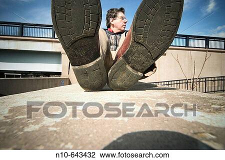 Close-up of the shoes of a man who is lying on a concrete slab. View Large Photo Image Stock Image - Close-up of the shoes of a man who is lying on a concrete slab.. Fotosearch
