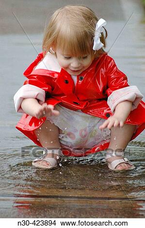 Picture - Close up of toddler girl playing in puddle. Fotosearch