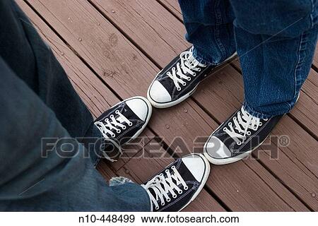 Stock Photo - Close-up of two teen boys? feet wearing identical sneakers and standing very close to each other. Fotosearch