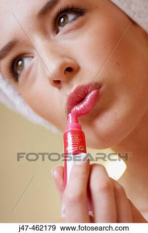 Stock Photo - close up of woman about apply red lipgloss. Fotosearch