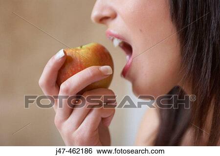Stock Photograph - close up of woman about to bite into an apple. Fotosearch