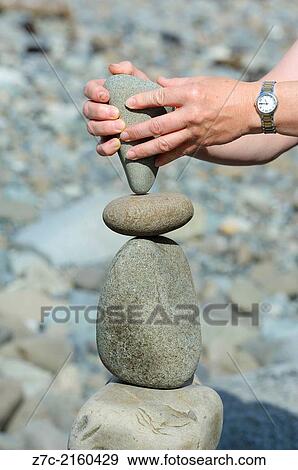 Close up of womans hands whilst she is carrying out the art of stone balancing on a beach. View Large Photo Image Stock Photo - Close up of womans hands whilst she is carrying out the art of stone balancing on a beach.. Fotosearch