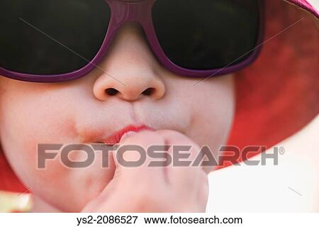 Close up of young girl with sunglasses and hat eating. View Large Photo Image Stock Photo - Close up of young girl with sunglasses and hat eating.. Fotosearch