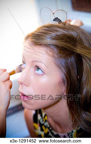 Stock Image - Close-up of young woman getting make-up put on. Fotosearch