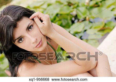 Close-up of young woman wearing green bikini, in a garden with water lilies in background View Large Photo Image Stock Photo - Close-up of young woman wearing green bikini, in a garden with water lilies in background. Fotosearch